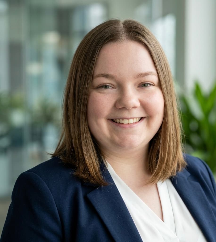 Smiling woman with brown hair wearing a navy blue blazer over a white shirt.