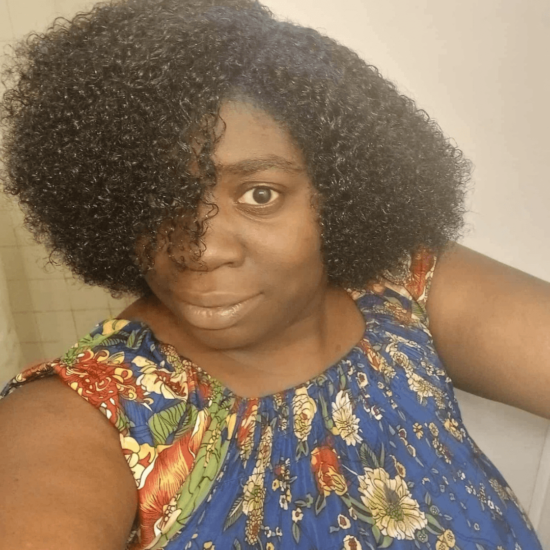 Black woman with short curly hair wearing a blue floral top, looking at the camera.